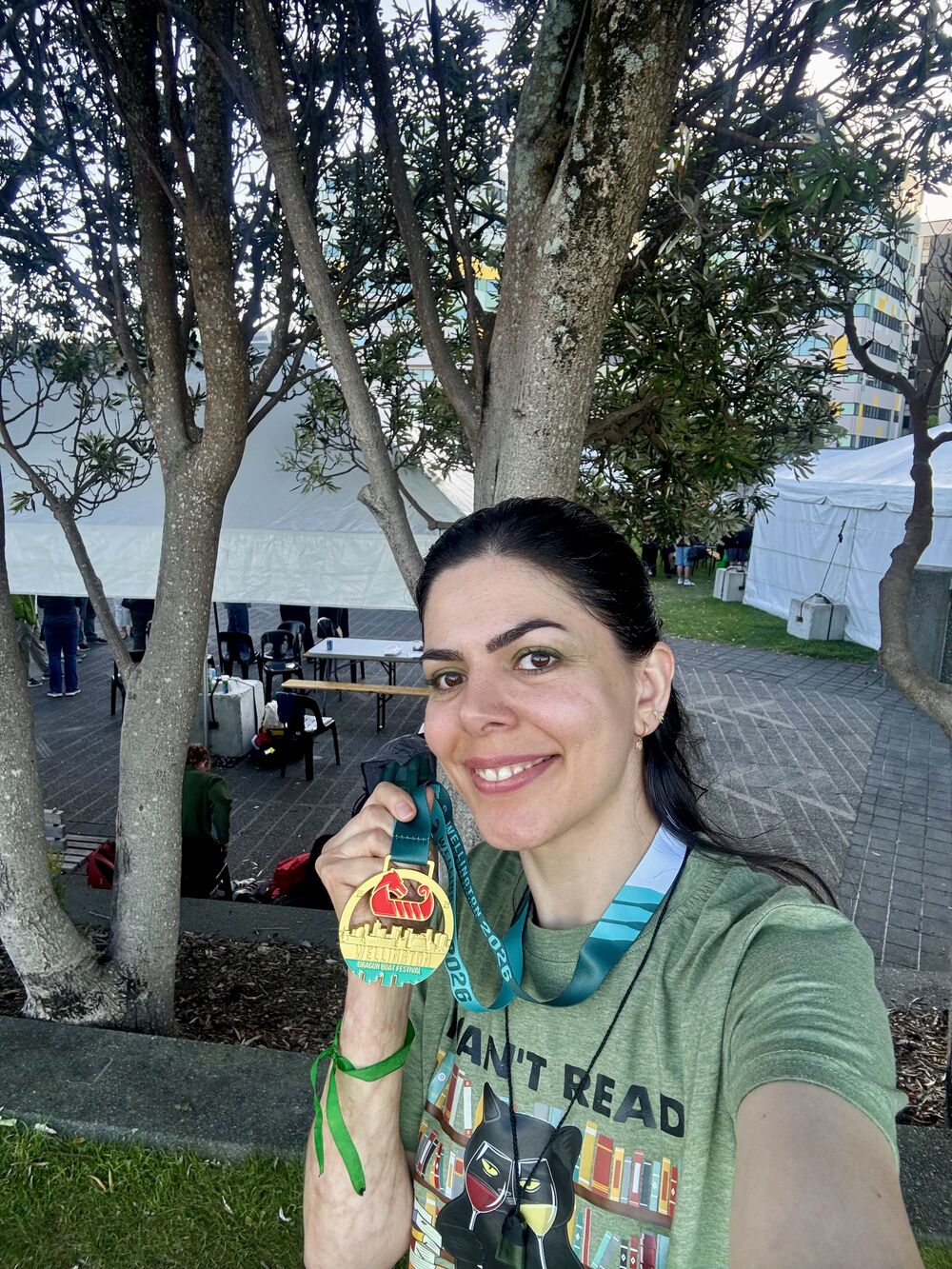 Mahnaz smiling and holding up a gold dragon boat festival medal